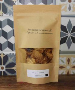 Sachet de rondelles d'ananas séchées, produit par Les Épices Curieuses, devant un carrelage coloré.