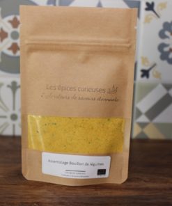 Assaisonnement de bouillon de légumes Les épices curieuses en sachet kraft, sur fond de carreaux colorés.