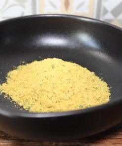 Assaisonnement en poudre jaune dans un bol noir sur fond de carreaux, parfait pour relever vos plats.