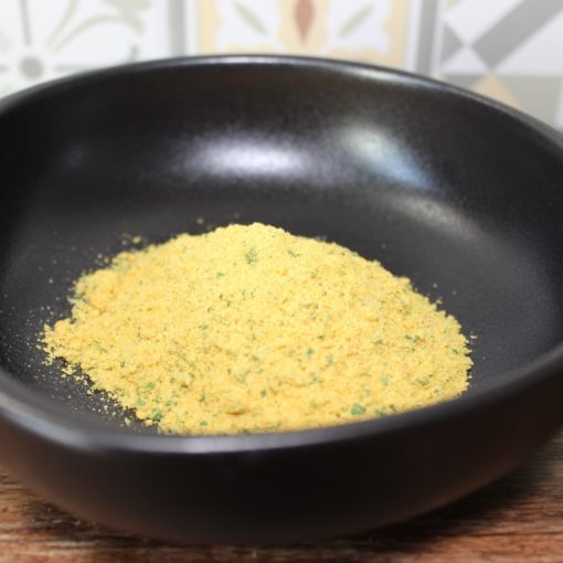 Assaisonnement en poudre jaune dans un bol noir sur fond de carreaux, parfait pour relever vos plats.