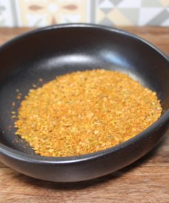 Bol noir d'épices colorées sur fond en bois, cuisine aromatique maison.
