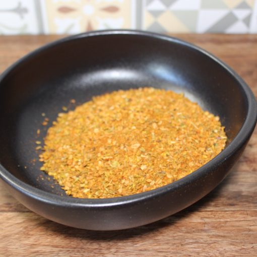 Bol noir d'épices colorées sur fond en bois, cuisine aromatique maison.