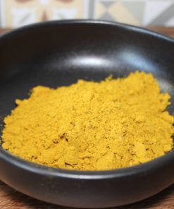 Poudre d'épices jaune vif dans un bol noir, idéale pour la cuisine exotique et recettes savoureuses.