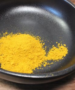Poudre de curry épicée dans un bol noir pour rehausser vos plats avec des saveurs exotiques.