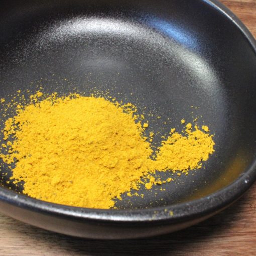 Poudre de curry épicée dans un bol noir pour rehausser vos plats avec des saveurs exotiques.