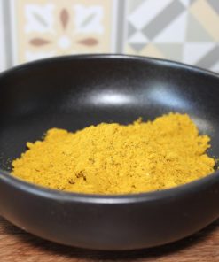 Bol de curry en poudre sur fond de carreaux colorés, épice clé pour rehausser les plats.