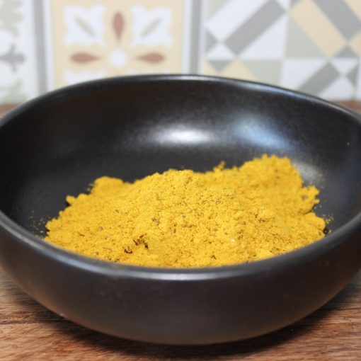 Bol de curry en poudre sur fond de carreaux colorés, épice clé pour rehausser les plats.
