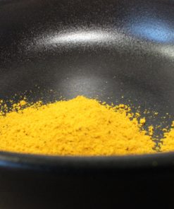 Poudre de curry jaune dans un bol noir, parfait pour ajouter de la saveur aux plats.