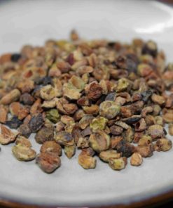 Graines de cardamome séchées posées sur une assiette blanche, épice aromatique utilisée en cuisine et pâtisserie.