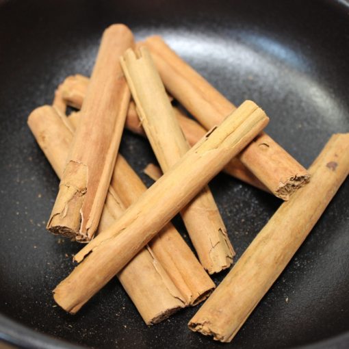 Bâtons de cannelle dans une poêle, parfaits pour infuser saveur et arôme aux plats et boissons chaudes.