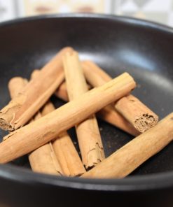 Bâtons de cannelle dans une poêle noire, parfaits pour des recettes aromatiques et chaleureuses.