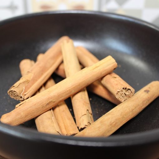 Bâtons de cannelle dans une poêle noire, parfaits pour des recettes aromatiques et chaleureuses.