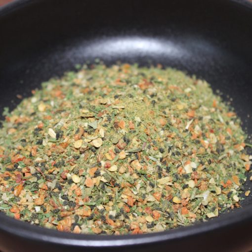 Assaisonnement épicé dans un bol noir, mélange coloré d'herbes et épices séchées pour rehausser vos plats.