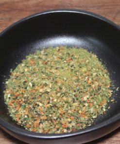 Mélange d'épices séchées dans un bol noir sur une table en bois, prêt pour la cuisine.