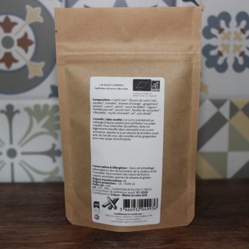 Sachet d'épices biologiques multicolores, fond fleuri. Composition variée: cumin, carottes, gingembre. Produit artisanal.