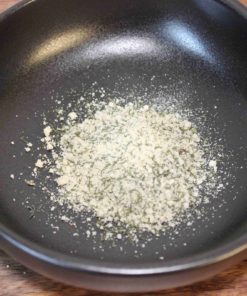 Poudre d'épices dans un bol noir sur une table en bois, prête pour la cuisine.