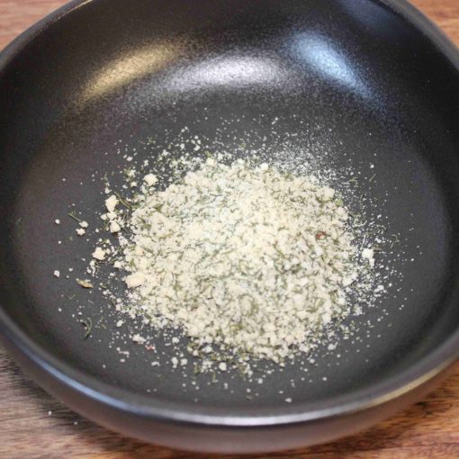Poudre d'épices dans un bol noir sur une table en bois, prête pour la cuisine.