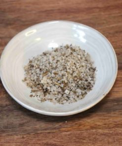 Bol de sel épicé mélangé avec herbes sur table en bois, prêt pour cuisiner.
