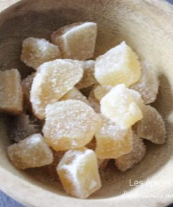 Morceaux de gingembre confit dans un bol en bois, délice sucré et épicé idéal pour agrémenter vos recettes exotiques.