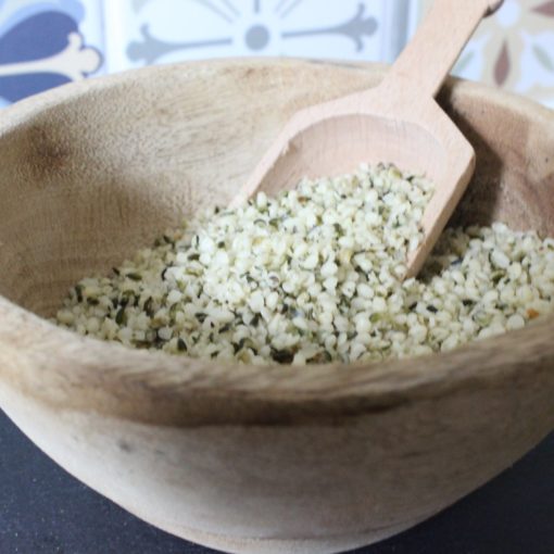 Bol en bois rempli de graines de chanvre biologiques avec cuillère en bois. Source de protéines et d'oméga-3.