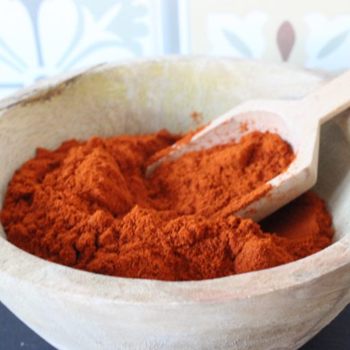 Paprika en poudre dans un bol en bois avec cuillère, parfait pour rehausser vos plats.