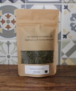 Sachet de paprika vert concassé par Les épices curieuses, sur fond de carrelage décoratif.
