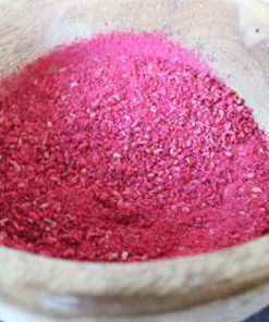 Poudre rouge brillante dans un bol en bois pour la cuisine ou la décoration naturelle.
