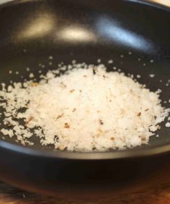 Sel de mer gourmet dans un bol noir, prêt à enrichir vos plats de sa saveur unique et délicate.