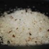 Tas de sel de mer finement moulu avec éclats bruns sur fond noir, gros plan.