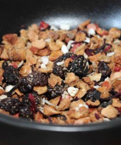 Mélange de fruits secs et baies dans un bol noir, prêt pour une infusion de tisane délicieuse et naturelle.