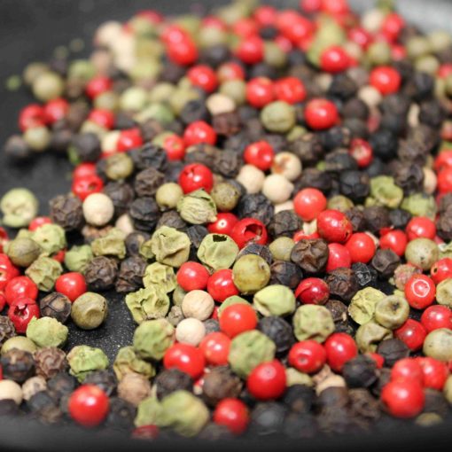 Mélange coloré de grains de poivre: rouge, noir, vert et blanc pour une cuisine épicée et aromatique.