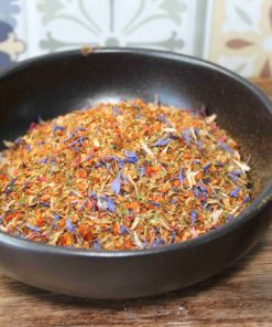 Bol d'épices colorées et fleuries sur une table en bois, idéal pour assaisonner vos plats avec style et saveur.