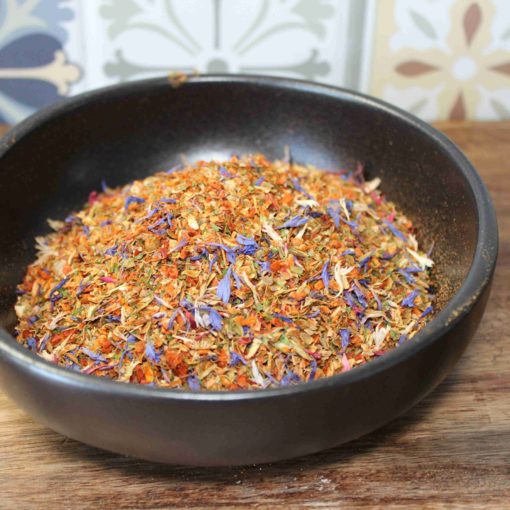 Bol d'épices colorées et fleuries sur une table en bois, idéal pour assaisonner vos plats avec style et saveur.