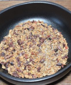 Bol de copeaux de cacao brut sur table en bois, parfait pour les recettes de desserts ou les snacks sains.