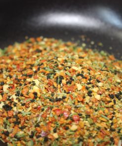 Mélange d'épices colorées dans une poêle, essentiel pour enrichir les saveurs culinaires avec des notes aromatiques variées.
