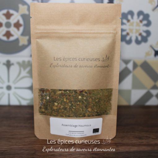 Mélange d'épices houmous par Les Épices Curieuses dans un sachet kraft, devant un fond décoratif.