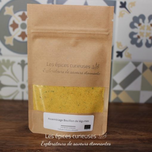 Assaisonnement de bouillon de légumes Les épices curieuses en sachet kraft, sur fond de carreaux colorés.