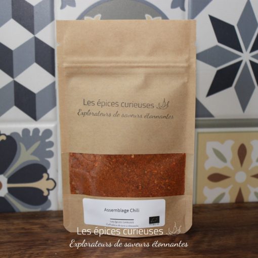 Mélange d'épices chili biologique des Épices Curieuses, en sachet kraft sur fond de carreaux décoratifs.