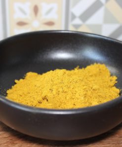 Bol de curry en poudre sur fond de carreaux colorés, épice clé pour rehausser les plats.