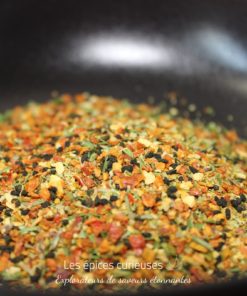 Mélange coloré d'épices et d'herbes dans un bol noir, idéal pour assaisonner vos plats et enrichir leurs saveurs.
