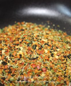 Mélange d'épices colorées dans une poêle, essentiel pour enrichir les saveurs culinaires avec des notes aromatiques variées.