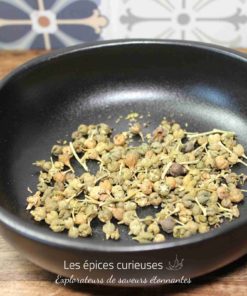 Graines séchées dans un bol noir sur une table en bois, avec des carreaux décoratifs en fond.
