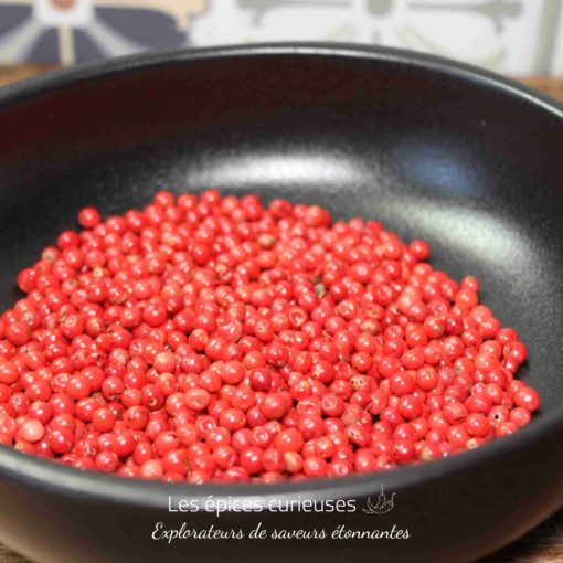 Assiette noire avec des baies rouges fraîches, prêtes pour la cuisine ou la décoration culinaire.