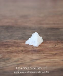 Cristal de sel en forme de pyramide sur une table en bois.