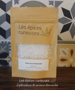 Fleur de sel Pyramide par Les Épices Curieuses, sur fond de carreaux géométriques. Gourmet et esthétique.