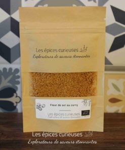 Sachet de fleur de sel au curry Les épices curieuses sur fond de carreaux décoratifs.