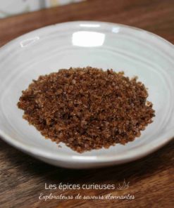 Sucre brun dans une assiette blanche sur une table en bois.