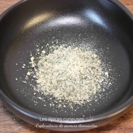 Poudre d'épices dans un bol noir sur une table en bois, prête pour la cuisine.