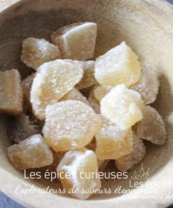 Morceaux de gingembre confit dans un bol en bois, délice sucré et épicé idéal pour agrémenter vos recettes exotiques.