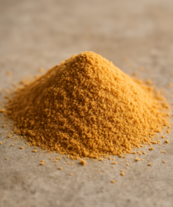 Tas de poudre jaune-orange sur surface grise, évoquant épices culinaires, ingrédients biologiques ou poudres alimentaires.